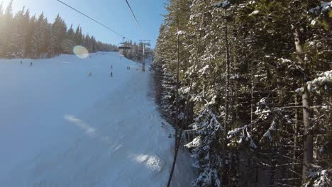 Ride-on-a-ski-lift-next-to-a-ski-track-between-trees