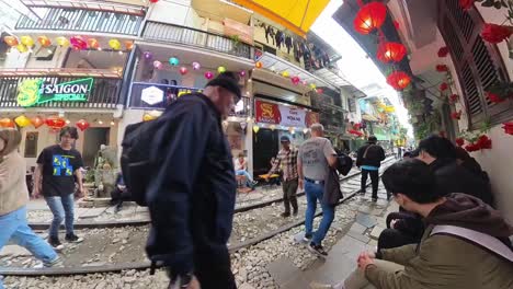 Timelapse-of-people-moving-close-to-buildings-on-both-sides-of-the-tracks-on-Hanoi-Train-Street,-a-narrow-train-bypass-