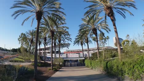 Palm-trees-lining-the-entrance-to-Dignity-Health-Sports-Park,-sunny-day-in-Carson,-California,-wide-shot