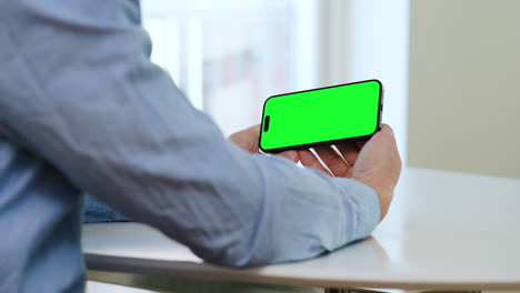 Man-holding-smartphone-two-hands,-green-screen-template