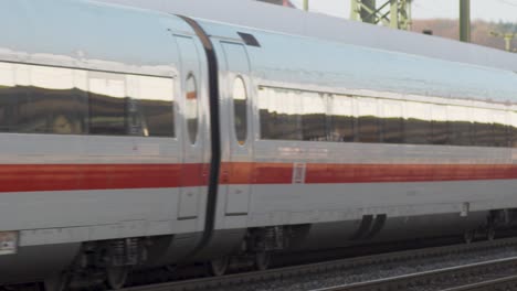 Blurred-train-speeding-through-a-station-with-waiting-passengers