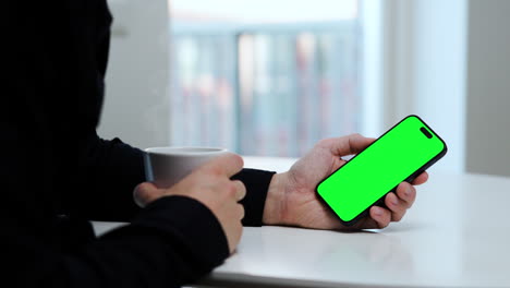 Man-holding-coffee-cup-and-smartphone,-green-screen-template