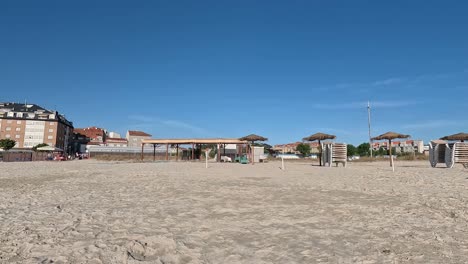 Edificios-En-Primera-Línea-De-Playa,-La-Gente-Viene-Por-La-Mañana-A-Tomar-El-Sol-Y-Bañarse,-Las-Sombrillas-Y-Tumbonas-Están-Recogidas-Y-Vacías,-Navegación-Descriptiva