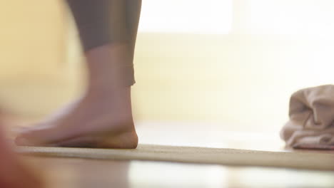 Low-angle-of-feet-as-lady-stretches-down-during-yoga-class-in-studio