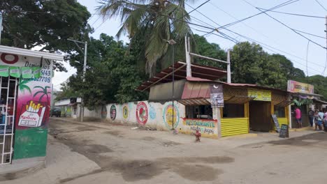 Street-view-of-a-colorful-store-and-mural-covered-walls-in-Palomino,-Colombia