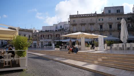 Piazza-della-Liberta-town-square-in-Ostuni,-Italy-with-cars-driving-in-late-afternoon