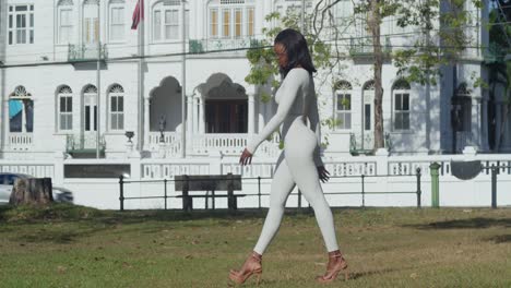 Una-Joven-Con-Un-Traje-Blanco-Aparece-En-Una-Ciudad-Caribeña,-Con-Castillos-Erguidos-Detrás-De-Ella.