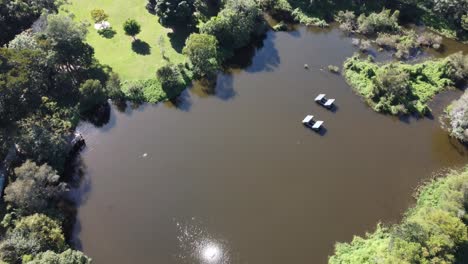 Aerial-view-of-a-small-lake-and-approaching-a-green-park-in-Australia