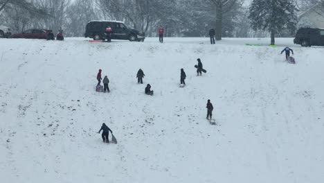 Niños-En-Trineo-Sobre-Una-Colina-Nevada-Durante-El-Día-De-Invierno-Sin-Escuela