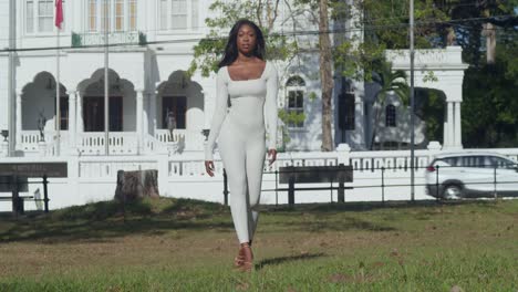 A-young-girl-in-a-white-bodysuit-explores-a-Caribbean-city,-with-castles-as-her-backdrop