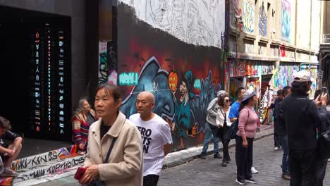 Turistas-Chinos-Paseando-Por-Hosier-Lane-En-La-Ciudad-De-Melbourne,-Una-Famosa-Calle-Que-Muestra-Una-Vibrante-Variedad-De-Murales-Artísticos-Y-Graffitis-Que-Adornan-Las-Paredes-Exteriores-De-Los-Edificios.