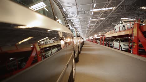 Filas-De-Coches-Nuevos-Y-Brillantes-Cargados-En-Un-Tren-De-Transporte-Multinivel-En-Un-Gran-Almacén-Industrial