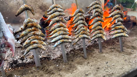 Sardinas-Tradicionales-Españolas-Espetos-Pescado-A-La-Parrilla-En-La-Playa-Sobre-Fuego-En-Brochetas-De-Metal-En-Marbella-Málaga,-Deliciosos-Mariscos-En-España,-Toma-De-4k