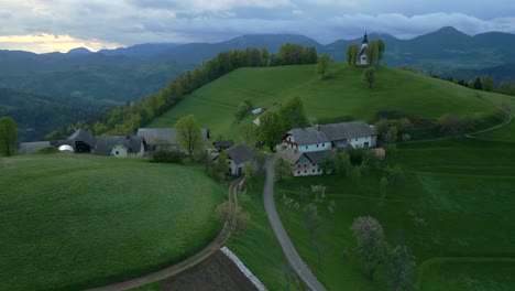 Vista-Del-Atardecer-De-La-Pintoresca-Iglesia-De-Nuestra-Señora-De-Los-Dolores-En-Bukov-Vrh,-Gorenja-Vas–poljane,-Eslovenia---Disparo-De-Drone-En-órbita