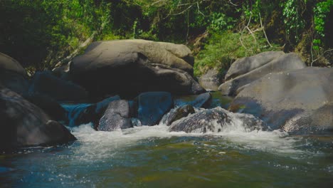 Clear-water-flowing-over-rocks-in-Khao-Sok-National-Park,-surrounded-by-lush-greenery