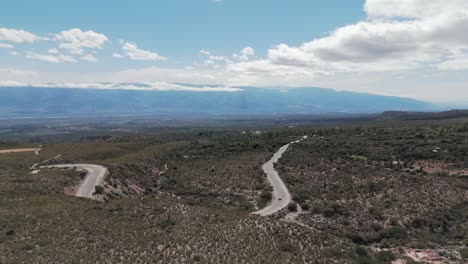 Aerial-above-Scenic-mountain-road-with-car-driving-in-Amaicha-del-Valle,-Argentina