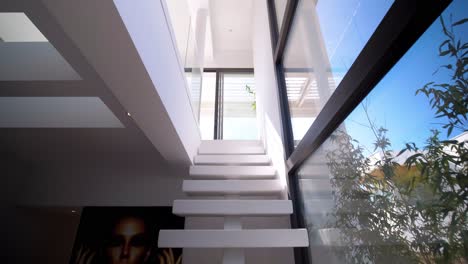 Slow-tilting-shot-of-beautiful-chandeliers-hanging-above-a-modern-staircase