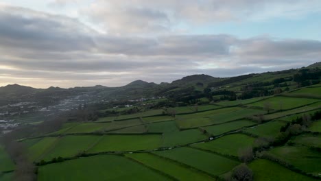 Vista-Panorámica-Aérea-De-Un-Pueblo-Al-Pie-De-La-Montaña-En-Un-Paisaje-Verde-Y-Exuberante