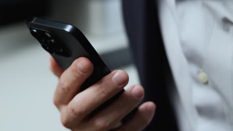 Man-in-dark-blue-jacket-and-light-blue-pin-stripe-shirt-looking-at-new-smartphone