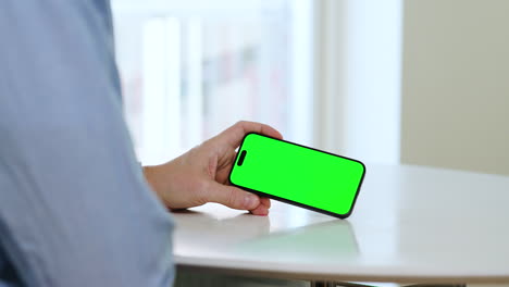 Man-holding-smartphone-in-left-hand,-landscape-mode,-green-screen-video-template