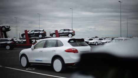 Shallow-focus-view-of-a-busy-car-lot-with-multiple-parked-and-stacked-vehicles,-cloudy-sky