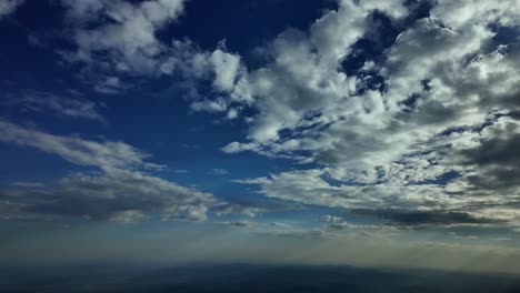 Pilot-POV-flying-in-deep-blue-sky-late-in-the-afternoon-with-some-tiny-white-clouds-in-the-sky