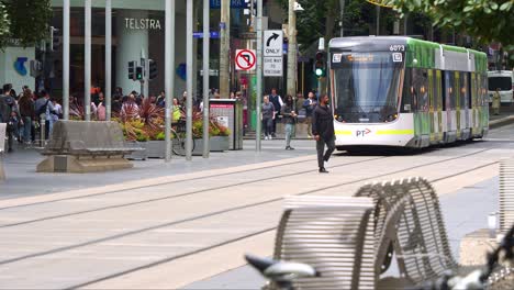 The-bustling-downtown-area-of-Melbourne-city,-filled-with-pedestrians-crossing,-shoppers-strolling-on-the-sidewalks,-and-trams-running-along-Bourke-Street,-slow-motion-shot