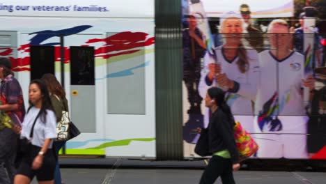 Slow-motion-shot-capturing-a-bustling-Melbourne-street-scene-in-downtown-central-business-district-with-trams,-pedestrians,-and-festive-decorations-reflecting-vibrant-urban-life