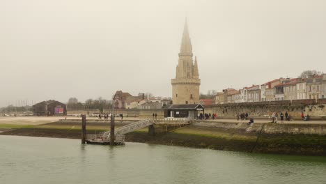 Profile-view-of-La-Rochelle-town,-France-on-a-mist-day-with-a-lake-in-foreground