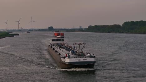 Bulk-carrier-sailing,-river-water,-wind-turbines-background,-slow-motion