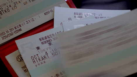 Colocar-Los-Billetes-De-Reserva-Del-Japan-Rail-Pass-Cuidadosamente-Apilados-Sobre-Una-Mesa-Simboliza-La-Planificación-Eficiente-Del-Viaje-Y-La-Conveniencia-De-Explorar-Los-Ferrocarriles-De-Japón.