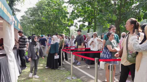 People-wait-in-line-for-the-Sunset-di-Kebun-outdoor-concert-event-under-the-shade-of-trees