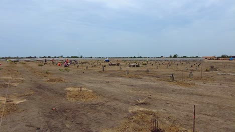 Panning-view-of-construction-workers-and-concrete-pile-molds-setup-for-solar-farm-construction