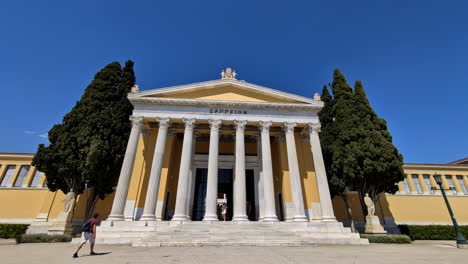 Historic-Zappeion-Hall-in-Athens,-Greece-with-a-clear-blue-sky-and-tall-trees-in-the-foreground