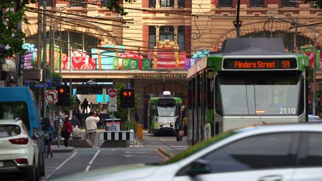 Slow-motion-shot-capturing-the-hustle-and-bustle-of-Melbourne-city,-with-pedestrians-crossing,-shoppers-strolling-on-the-sidewalks,-cars-driving,-and-trams-running-along-Elizabeth-Street