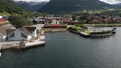 Luftaufnahme-Des-Stadtzentrums-Von-Vikøyri-Mit-Menschen-Auf-Einem-SUP-Board