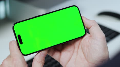 Hands-holding-smartphone-in-landscape-mode,-green-screen-video-template