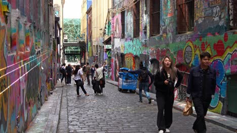 Los-Turistas-Acuden-En-Masa-A-Hosier-Lane-En-La-Ciudad-De-Melbourne,-Una-Famosa-Calle-Que-Muestra-Una-Vibrante-Variedad-De-Murales-Artísticos-Y-Graffitis-Que-Adornan-Las-Paredes-Exteriores-De-Los-Edificios,-Tomas-En-Cámara-Lenta