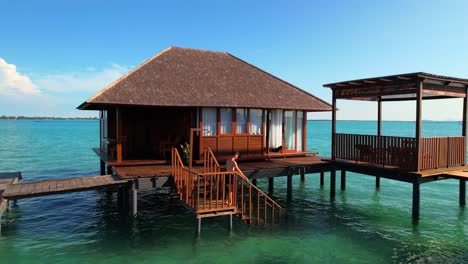 Man-enjoying-vacation-by-swimming-in-the-sea-at-an-overwater-bungalow-villa-in-Leebong-Island,-Belitung-Indonesia