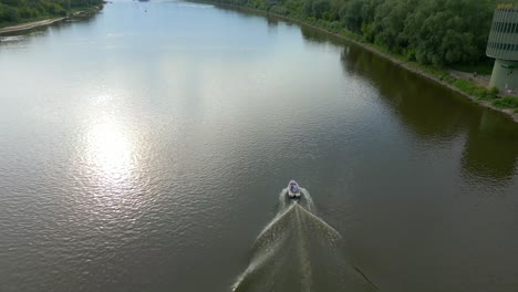 Aerial-tracking-small-motorboat-transport,-still-and-calm-river-waters