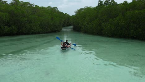 Static-aerial-view-of-a-young-couple-kayaking-or-canoeing-through-a-mangrove-river-forest-in-Belitung-Indonesia