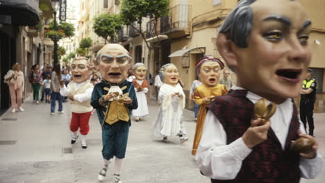 Giant-masks-parade-through-Castellón-de-la-Plana-streets-for-Corpus-Christi-2024,-handheld-smooth-camera-captures-festive-atmosphere