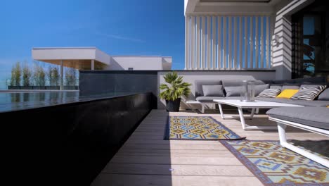 Slow-dolly-shot-along-a-swimming-pool-on-a-balcony-with-furniture