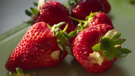 Fresh-Strawberries-with-Green-Leaf-Tops-Lying-on-Chopping-Board-in-Golden-Hour-Light