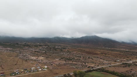 Scenic-aerial-view-of-city-Tafì-del-Valle-and-cloudy-mountainscape-in-Tucumán,-Argentina