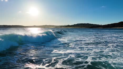 Aerial-view-of-surfer-nearly-taking-off-on-ocean-wave-at-beautiful-sunset