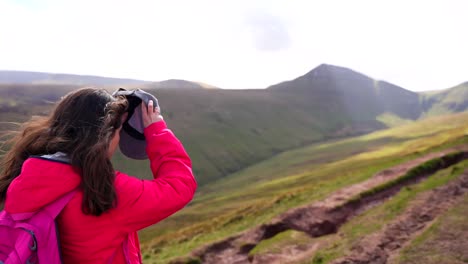 Backpacker-woman-puts-on-cap-and-hikes-towards-Pen-y-Fan-Mountain-on-a-sunny-day