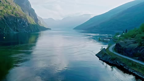 Aerial-drone-forward-moving-shot-over-water-fjord,-surrounded-by-mountains-in-Aurland,-Norway-at-daytime