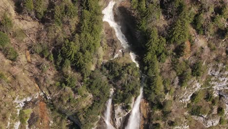 Aerial-view-of-Seerenbach-Falls-with-twin-cascades-flowing-down-a-rugged-cliff-face-surrounded-by-greenery-in-Amden,-Betlis,-near-Walensee,-Switzerland