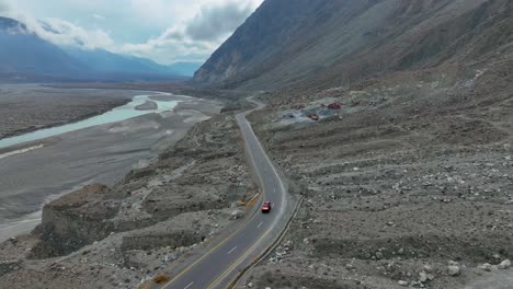 Winding-mountain-road-near-Nomal-in-Gilgit-Baltistan,-with-a-flowing-river-and-rugged-terrain